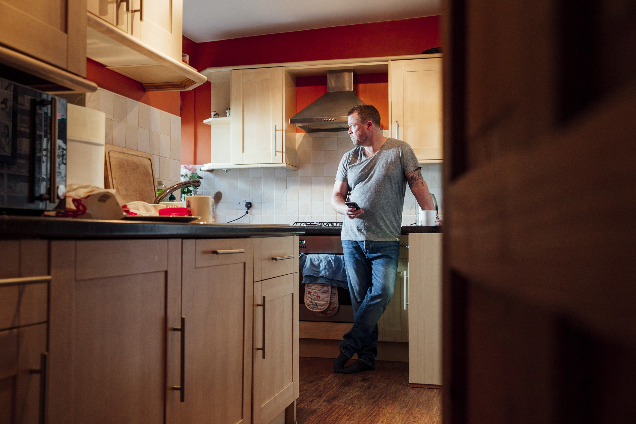 Middle-aged man stands in kitchen thinking quietly to himself.